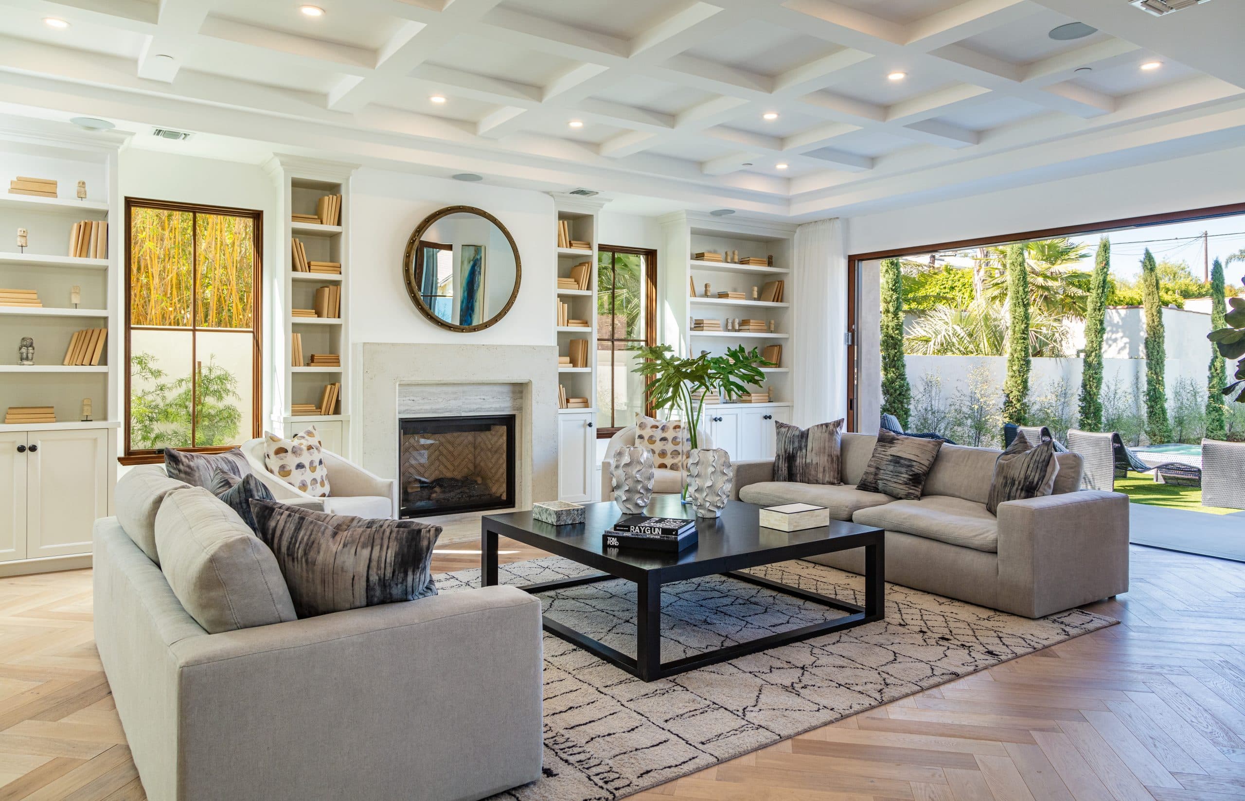 Bright living room with coffered ceiling, built-in bookshelves, and large windows